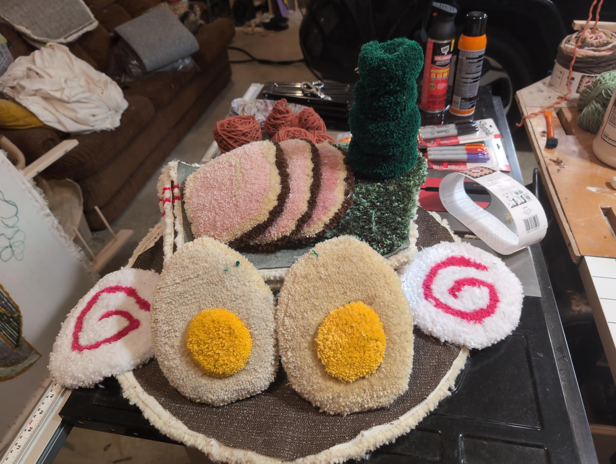 All the finished ingredients laid out together on the round broth base before assembly: naruto discs, egg halves, chashu, nori, and green onion rings